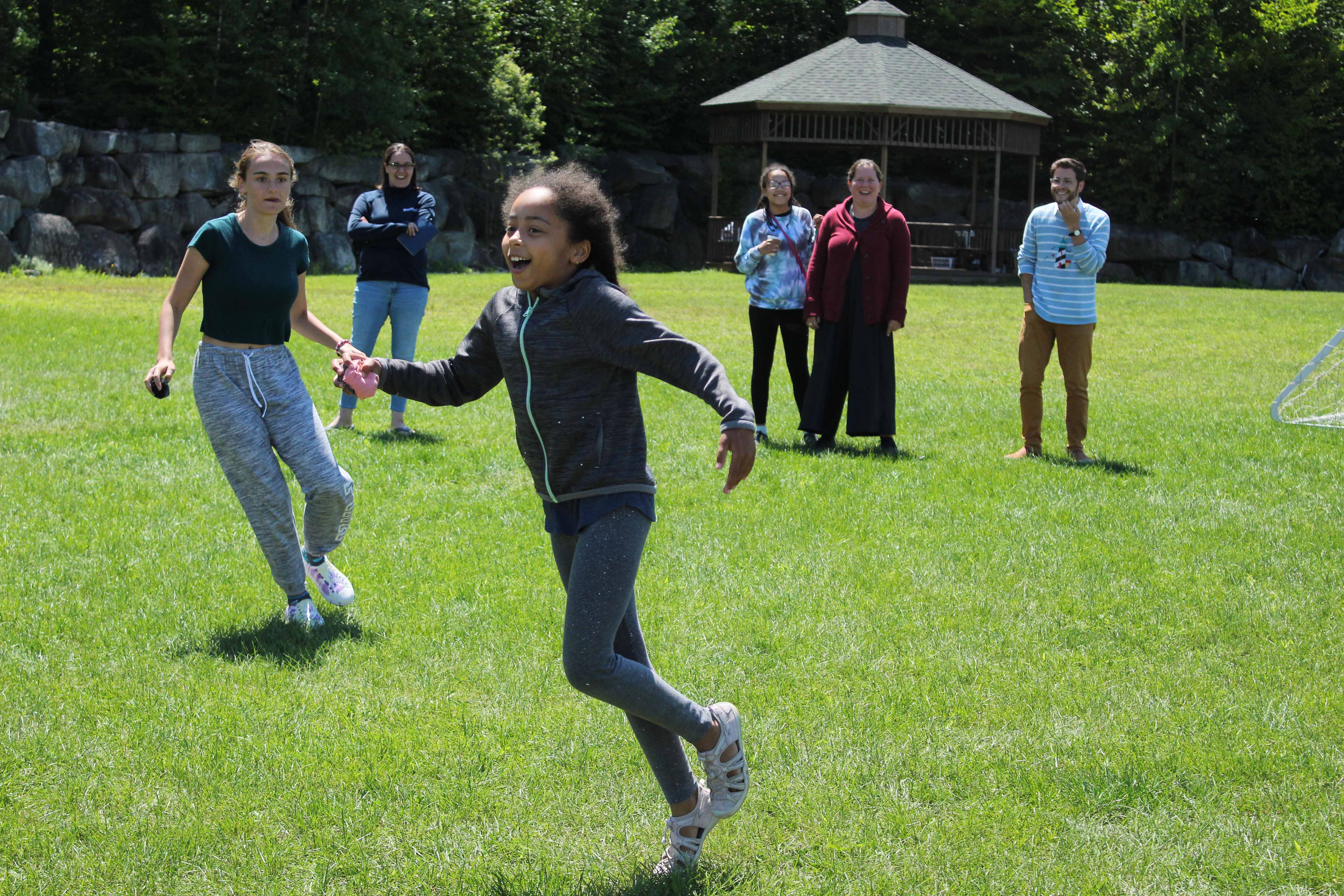 A camper laughs and runs as others cheer them on.